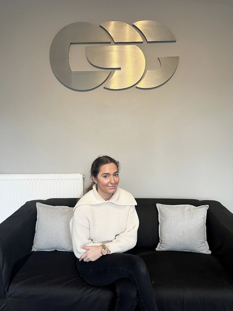 Molly pictured sitting on a sofa in front of a CSG sign.